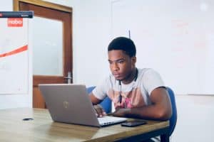 young male on laptop studying GCSE English and Maths resit courses at NEC