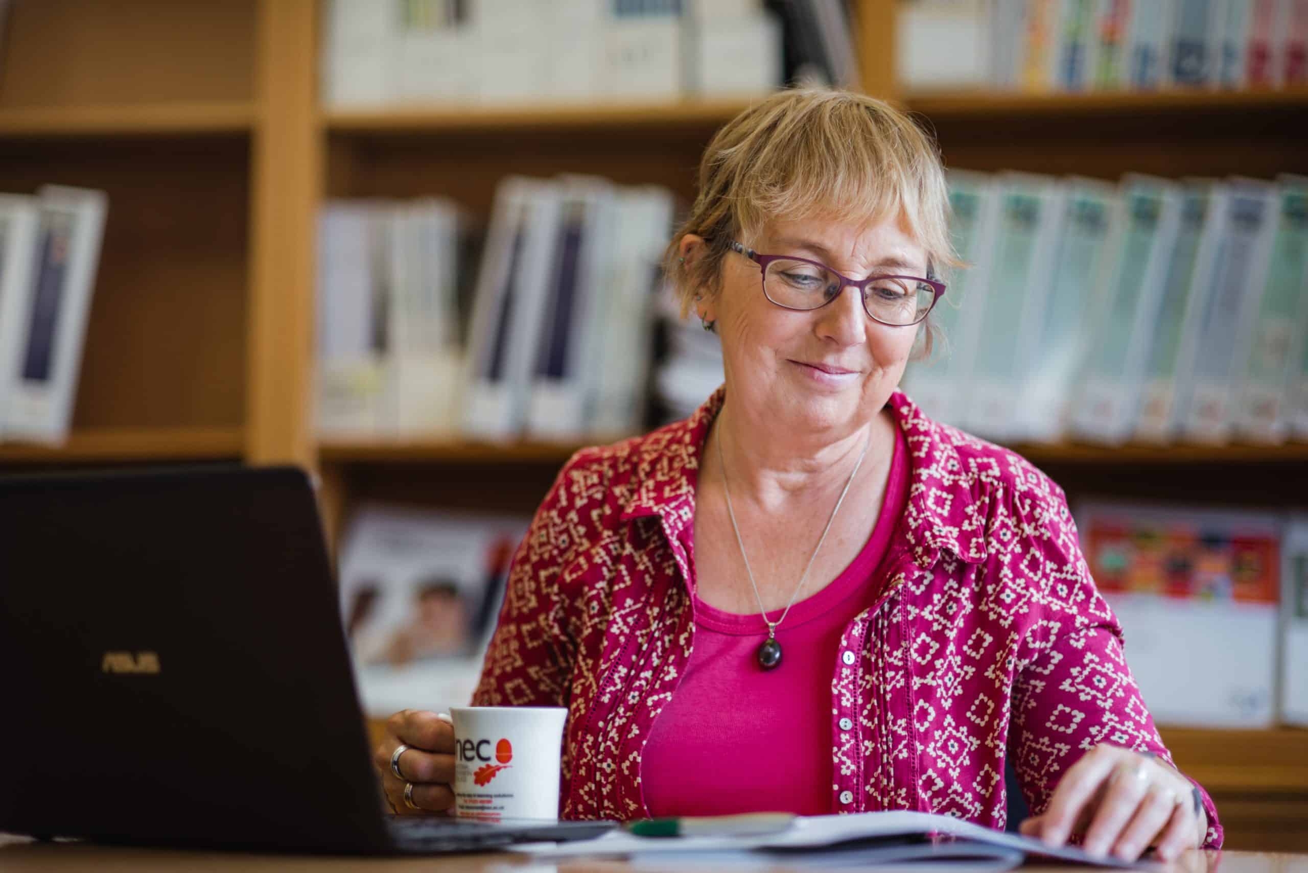 NEC employee friendly NEC employee at desk. Ready to help NEC distance learning students with their online study